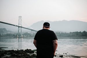 photo of a man looking out at the river and bridge