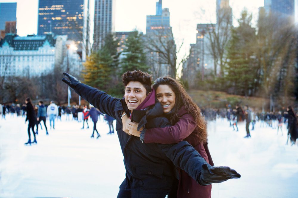 happy young couple ice skating in new york city