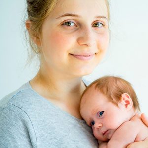 A woman smiles while holding a baby in her arms