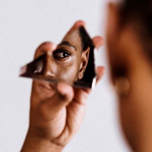 A person is looking at their reflection in a broken mirror