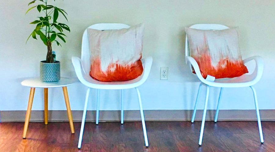 Resilient Self Therapy - Two white chairs with orange pillows and a plant on a table in Kingston, New York